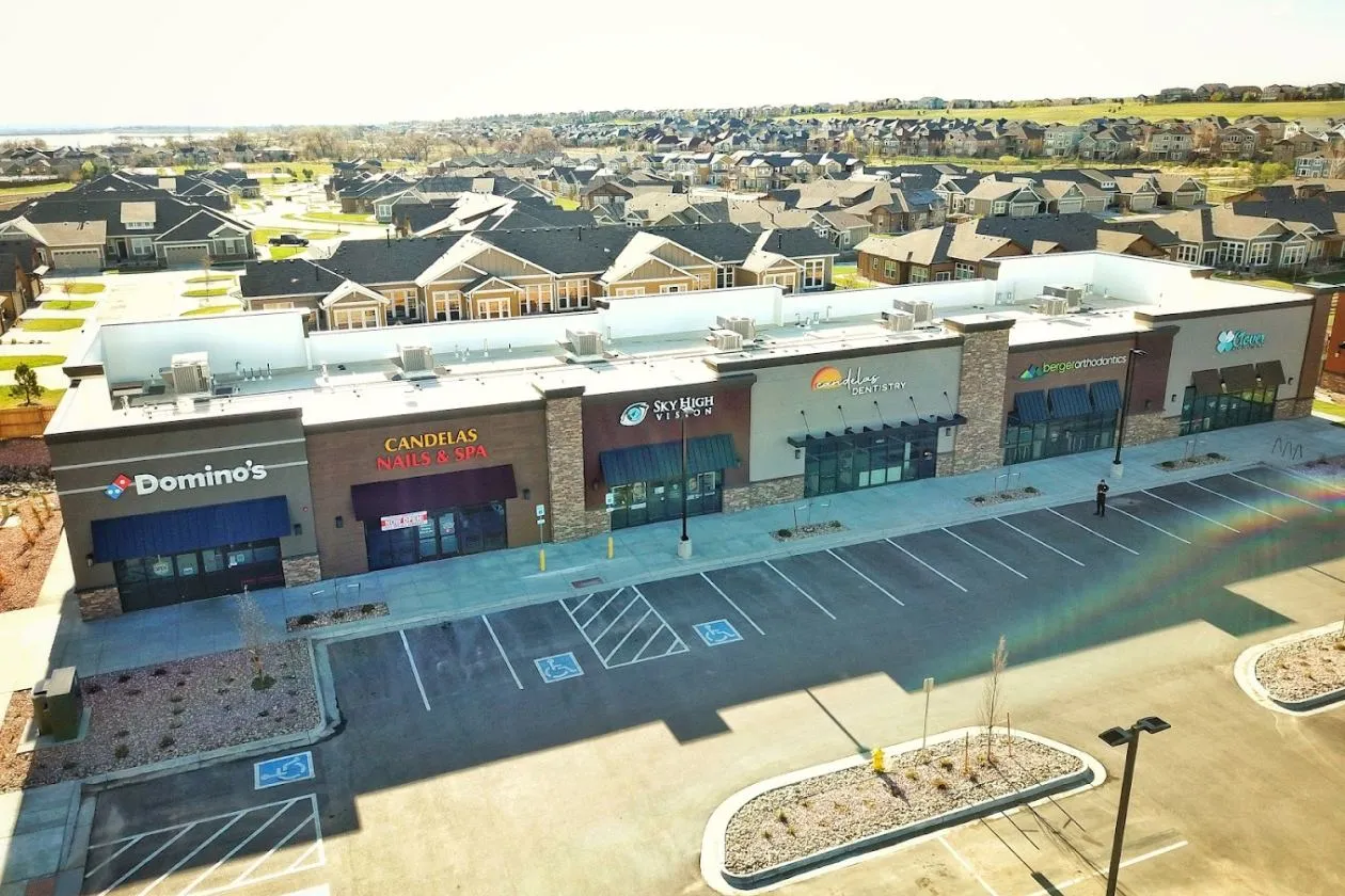 Outdoor shopping plaza with various stores near the Arvada office