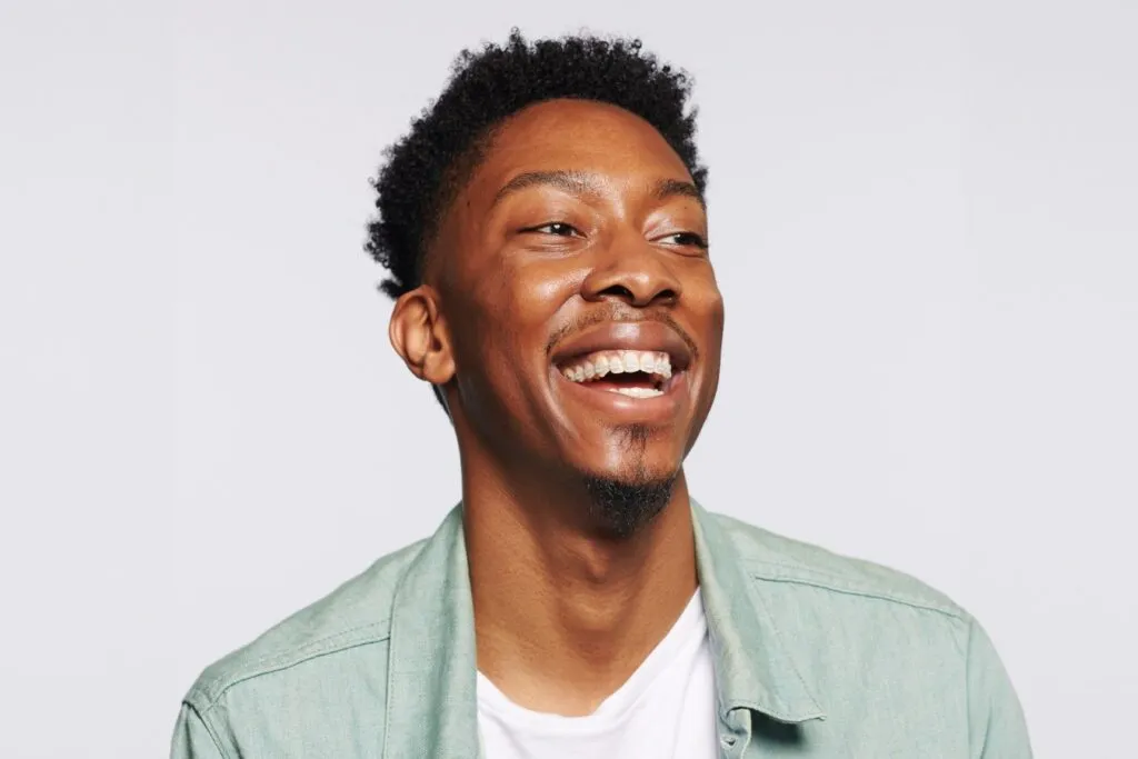 Smiling young man with straight teeth, showcasing the benefits of orthodontic treatment options like Invisalign and braces.