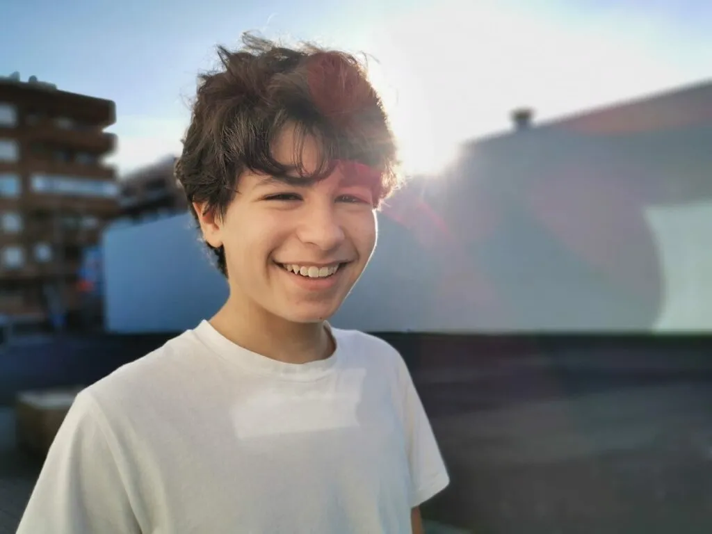 Smiling teenager outdoors, showcasing a bright smile, representing the positive impact of orthodontic treatment options like braces and clear braces for teens at Bergen Orthodontics.